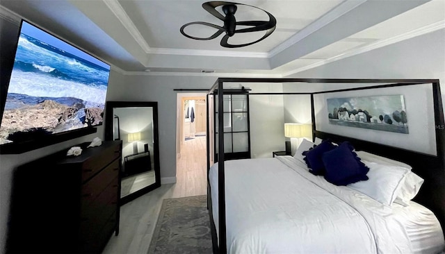 bedroom with a tray ceiling, visible vents, crown molding, and wood finished floors