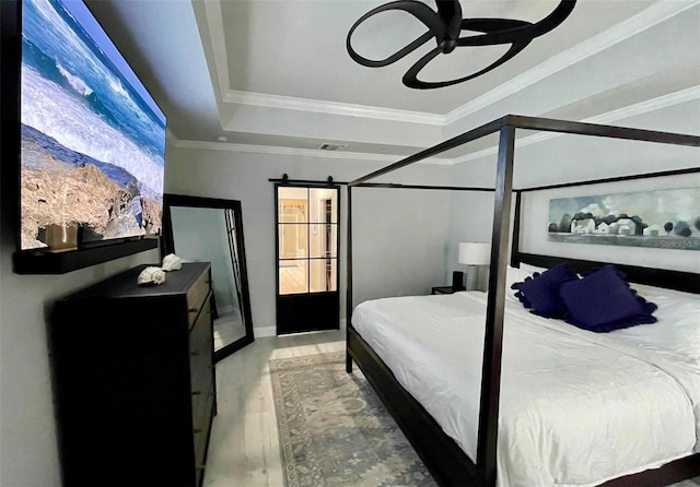 bedroom with a barn door, visible vents, a raised ceiling, wood finished floors, and crown molding