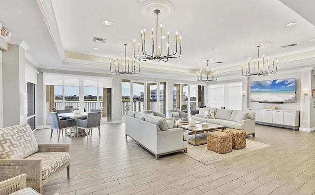 living area with visible vents, light wood-style flooring, a tray ceiling, crown molding, and a chandelier