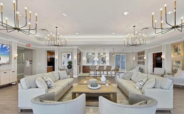 living area featuring a chandelier, a raised ceiling, and crown molding