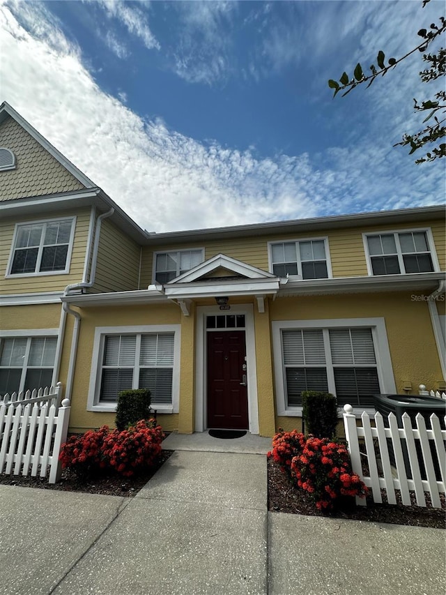 townhome / multi-family property with a fenced front yard and stucco siding