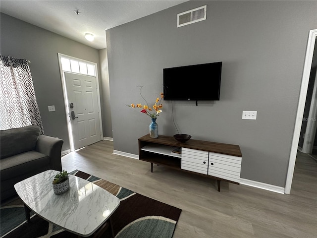 living room with light wood-type flooring, baseboards, and visible vents