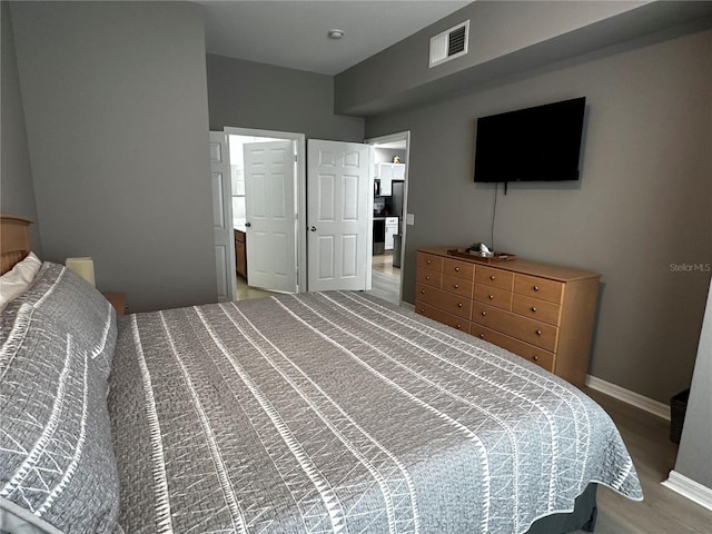 bedroom featuring visible vents, baseboards, and wood finished floors