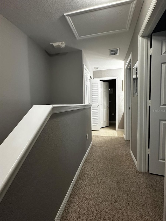 hall with visible vents, an upstairs landing, baseboards, carpet, and attic access