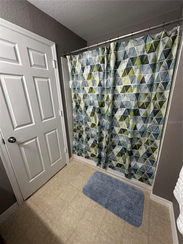 bathroom with a textured wall and a textured ceiling