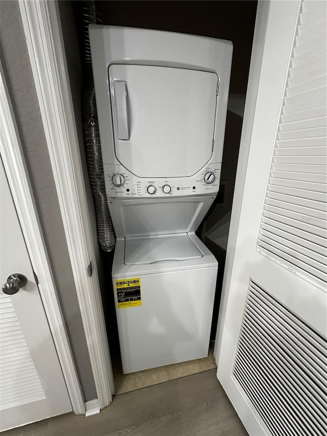 clothes washing area featuring laundry area, dark wood-style floors, and stacked washer / drying machine