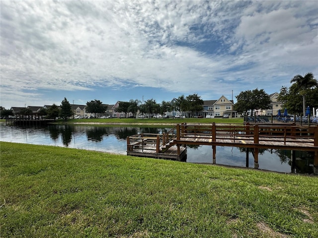 dock area with a water view, a residential view, and a lawn