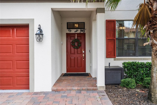 property entrance with an attached garage and stucco siding