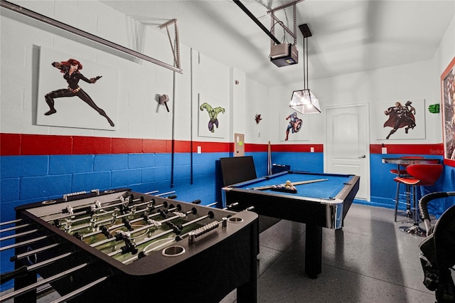 playroom with a garage, concrete block wall, billiards, and speckled floor