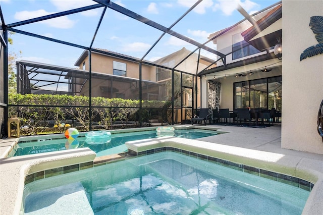 view of swimming pool with glass enclosure, a patio area, and a pool with connected hot tub