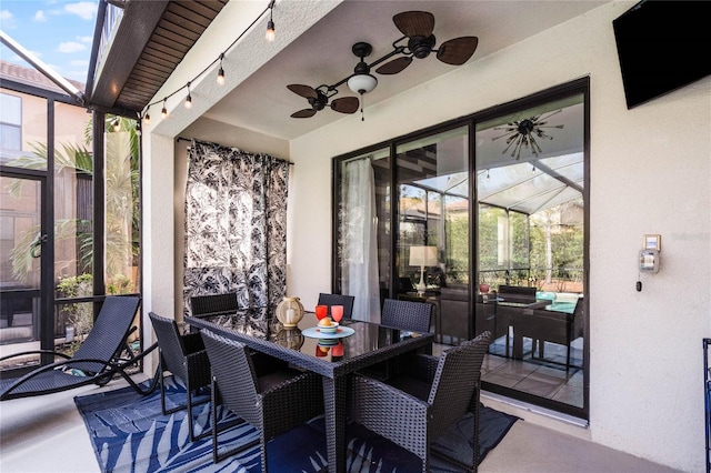 view of patio / terrace featuring a ceiling fan, outdoor dining space, and glass enclosure