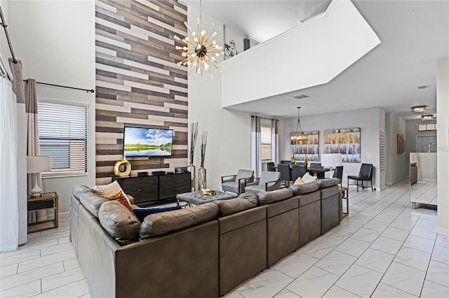 living room with a chandelier, marble finish floor, a high ceiling, and visible vents