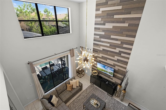 living room featuring baseboards, light tile patterned floors, a towering ceiling, and a notable chandelier