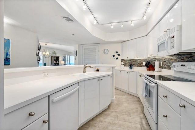 kitchen featuring white appliances, a sink, visible vents, white cabinets, and decorative backsplash