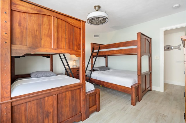 bedroom with light wood-style floors, visible vents, and baseboards