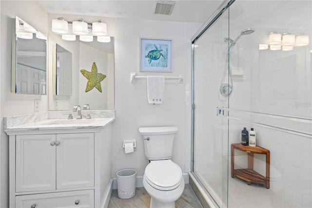 full bath featuring toilet, a stall shower, vanity, and visible vents