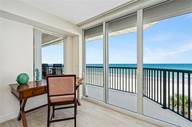 sunroom / solarium featuring a beach view and a water view