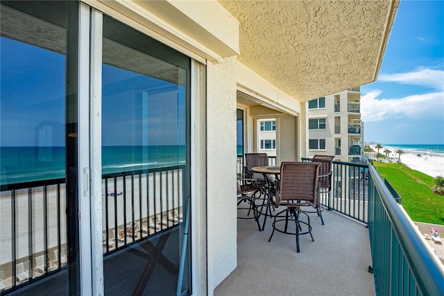 balcony featuring a view of the beach and a water view