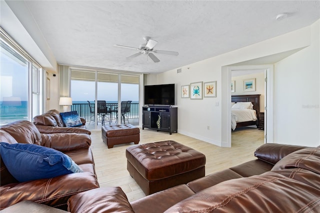 living area featuring expansive windows, light wood finished floors, a textured ceiling, and visible vents