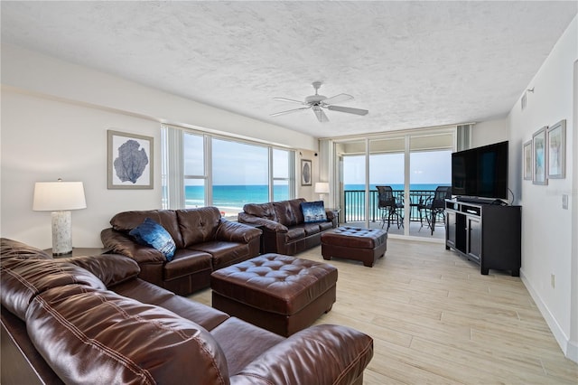 living room with visible vents, light wood-style flooring, expansive windows, ceiling fan, and a textured ceiling