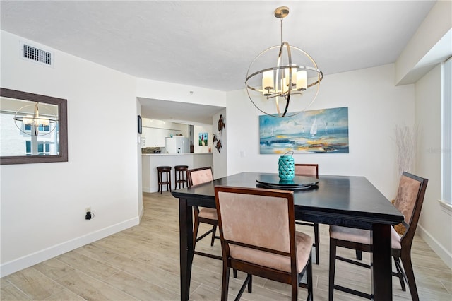 dining area featuring light wood finished floors, baseboards, visible vents, and a notable chandelier