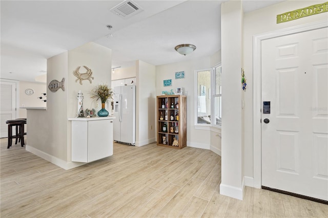 foyer featuring light wood finished floors, visible vents, and baseboards