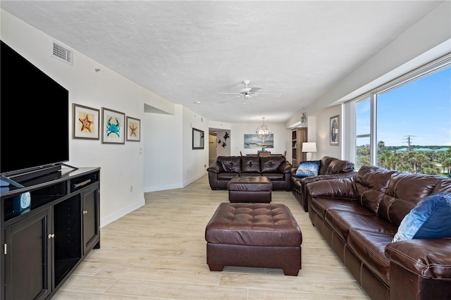 living room featuring baseboards, visible vents, a ceiling fan, a textured ceiling, and light wood-type flooring