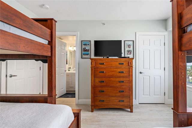 bedroom with light wood finished floors, baseboards, and connected bathroom