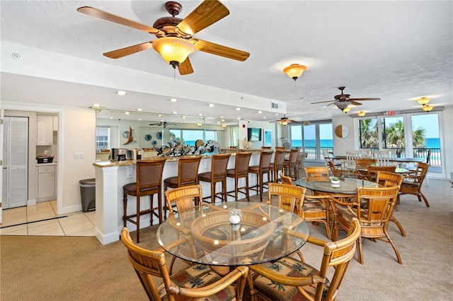 dining space featuring visible vents, light carpet, a textured ceiling, and light tile patterned floors