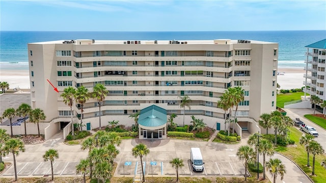 view of building exterior featuring a water view and a beach view