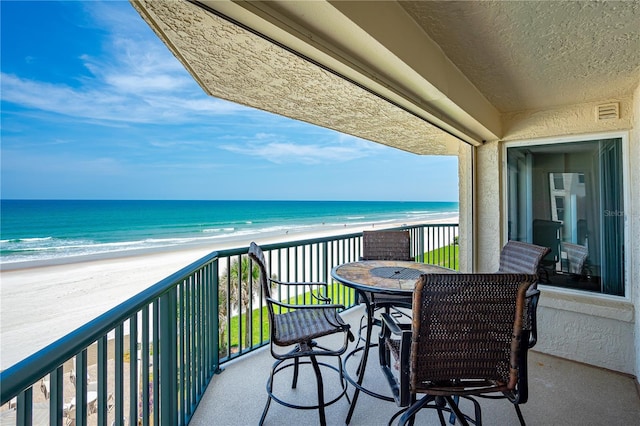 balcony with visible vents, a water view, and a view of the beach