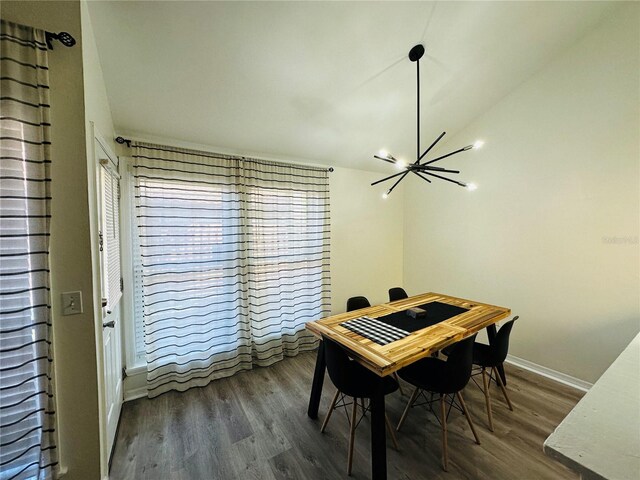 dining room with a notable chandelier, hardwood / wood-style flooring, and vaulted ceiling