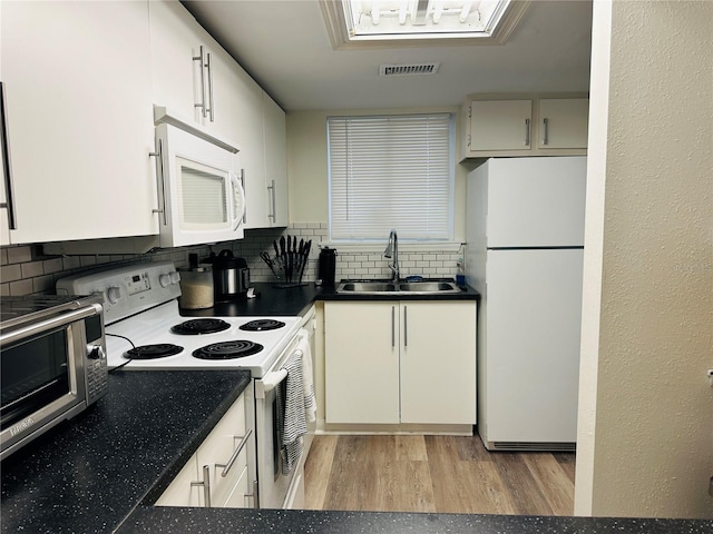 kitchen with white appliances, light wood-type flooring, backsplash, sink, and white cabinetry