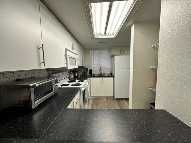 kitchen with tasteful backsplash, light wood-type flooring, white appliances, and white cabinetry