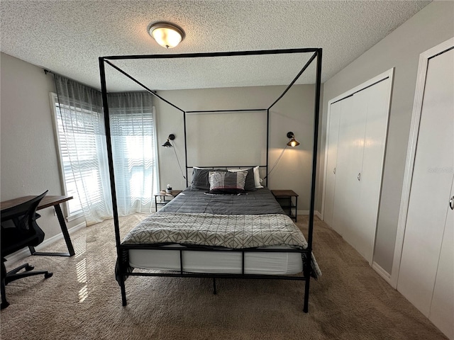 bedroom with a textured ceiling, multiple closets, and carpet floors