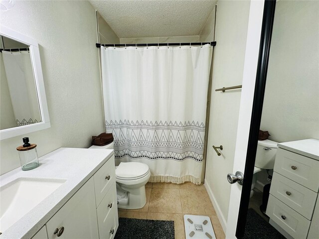 bathroom featuring tile patterned floors, vanity, a textured ceiling, and toilet