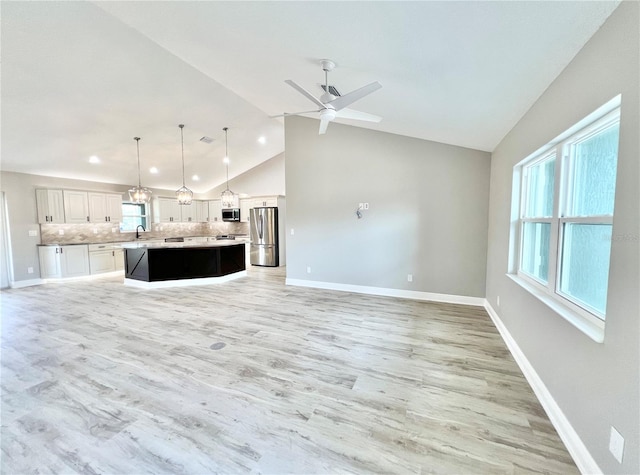 unfurnished living room featuring high vaulted ceiling, light wood-type flooring, sink, and ceiling fan