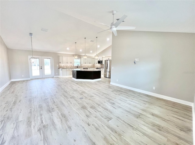 unfurnished living room featuring ceiling fan, french doors, high vaulted ceiling, light hardwood / wood-style floors, and sink