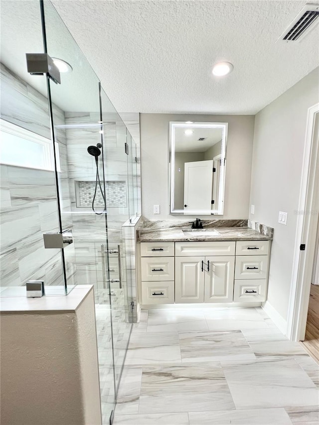 bathroom with a textured ceiling, walk in shower, tile patterned floors, and vanity