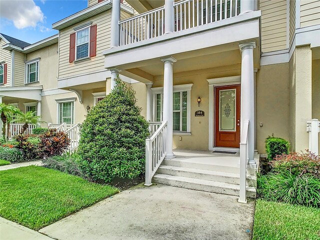 property entrance with covered porch and a balcony