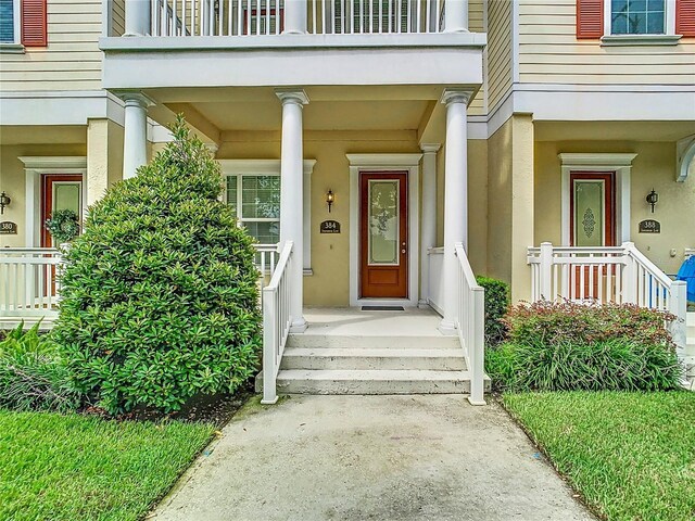 doorway to property with a balcony and a porch