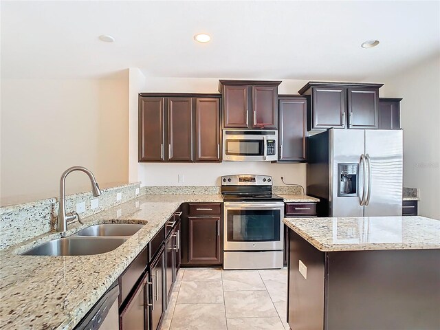 kitchen featuring light tile patterned floors, appliances with stainless steel finishes, light stone countertops, sink, and dark brown cabinetry