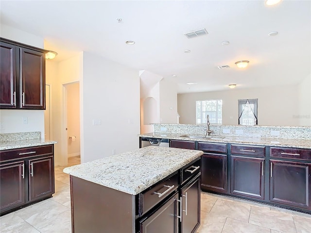 kitchen featuring light stone counters, light tile patterned floors, sink, and a kitchen island