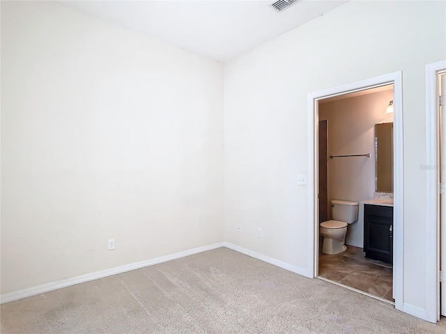 unfurnished bedroom featuring ensuite bathroom and light carpet