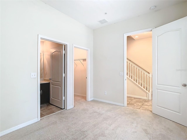 unfurnished bedroom with a spacious closet, light colored carpet, and a closet