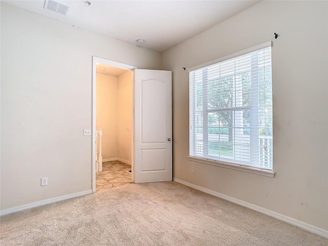 unfurnished bedroom featuring light carpet and multiple windows