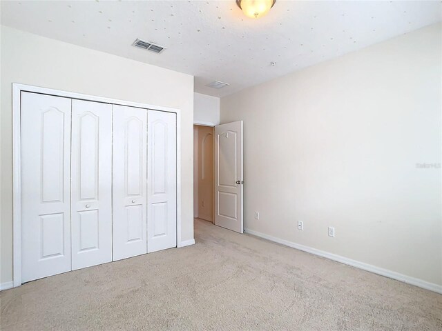 unfurnished bedroom featuring light carpet and a closet