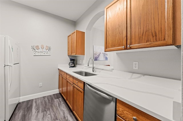 kitchen featuring dishwasher, light stone countertops, wood-type flooring, sink, and white fridge