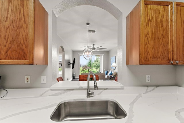 kitchen featuring ceiling fan, sink, and light stone countertops