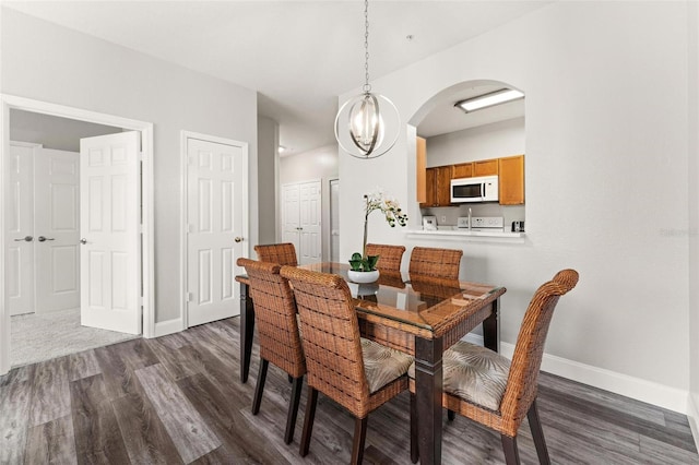 dining area featuring dark wood-type flooring and an inviting chandelier